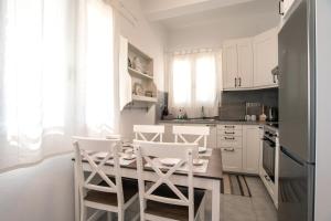 cocina con armarios blancos, mesa y sillas en Punda Beach Seaside Retreat en Logaras