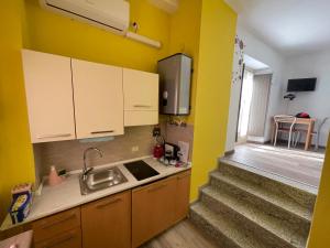 a kitchen with yellow walls and a sink and a staircase at Rossana Apartment Lago Maggiore in Baveno