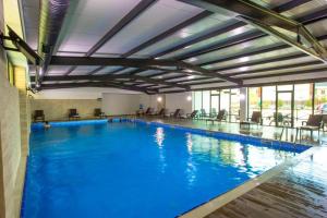 a large pool with blue water in a building at Crystal Wood in Bakuriani