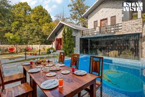 an outdoor dining area with a table and a swimming pool at Amaltas with Pvt Pool & Lawn By StayVista in Rāmnagar