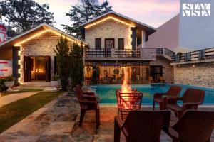 a house with a swimming pool and a fire place at Amaltas with Pvt Pool & Lawn By StayVista in Rāmnagar