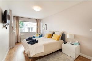 a white bedroom with a large bed with yellow pillows at Appartement 75006 paris ! in Paris