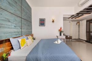 a bedroom with a blue bed with a wooden headboard at Amaltas with Pvt Pool & Lawn By StayVista in Rāmnagar