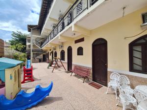 a building with chairs and tables and a playground at Pousada Aquários in Cabo Frio