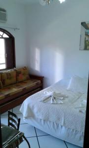 a bedroom with a bed and a couch at Pousada Aquários in Cabo Frio