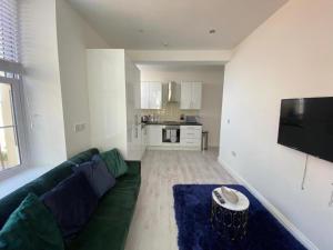a living room with a green couch and a kitchen at Beautiful 1-Bed Apartment in Walton on the Naze in Walton-on-the-Naze