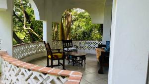 porche con sillas, mesa y ventana en Pretty Holiday Homes, en Mombasa