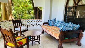 sala de estar con sillas, sofá y mesa en Pretty Holiday Homes, en Mombasa