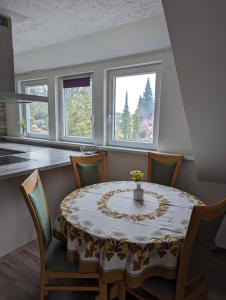 a dining room with a table and chairs and two windows at Nepalaya Ferienwohnung in Pegnitz