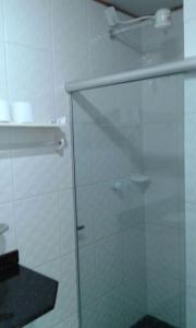 a bathroom with a glass shower door with a shelf at Pousada Aquários in Cabo Frio