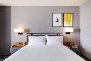嘉義市にあるvoco Chiayi, an IHG Hotelのベッドルーム(白い大型ベッド、ランプ2つ付)