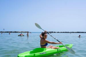 a woman sitting on a kayak in the water at Hotel San Salvador in Bellaria-Igea Marina