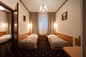a hotel room with two beds and a window at Hotel Trylogia in Zielonka