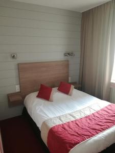 a bedroom with a bed with two red pillows on it at Hôtel-restaurant Les Colonnades in Saint-Fulgent