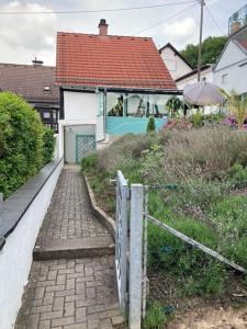 uma casa com um portão e um passadiço de tijolos em Apartment mit Wintergarten und Terrasse in ruhiger Lage im schönen Taunus em Glashütten