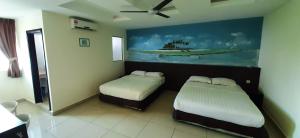 a room with two beds and a painting on the wall at Sipadan Inn Service Apartments Semporna in Semporna