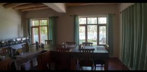 a dining room with a table and chairs and windows at LADAKH ODYSSEY Hotel in Leh