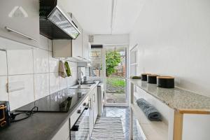 a white kitchen with a sink and a counter at Cosy Tottenham Apartment Sleeps 4 in London