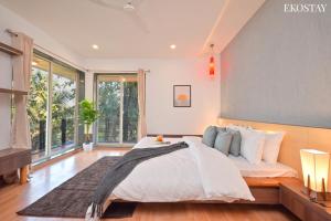 a bedroom with a large bed and a large window at EKOSTAY Gold - Amara Villa in Alibaug