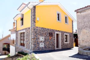 ein gelbes Haus mit einer Steinfassade in der Unterkunft Casa Rural La Tayuela in Luanco