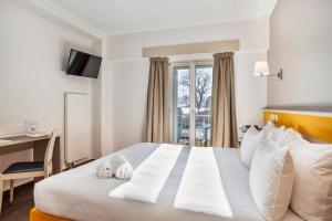 a hotel room with a bed with a desk and a window at Hotel La Longeraie in Morges