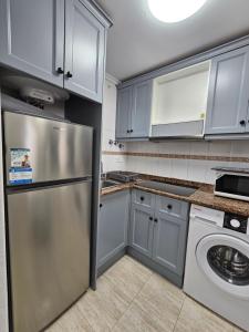 una cucina con frigorifero in acciaio inossidabile e armadietti bianchi di Apartamento Benimar Beach a Benidorm