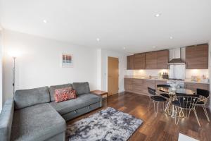 uma sala de estar com um sofá, uma mesa e uma cozinha em Modern Shoreditch flat next to station with lift and views em Londres
