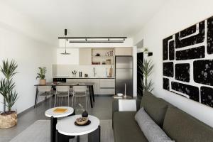 a living room with a couch and tables and a kitchen at Mr Rothschild By TLV2GO in Tel Aviv