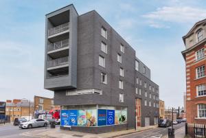 een groot grijs gebouw in een stadsstraat bij Modern Shoreditch flat next to station with lift and views in Londen