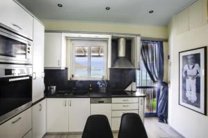 een keuken met witte kasten, een wastafel en een raam bij Nelly's Private Resindence in Chania