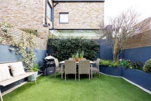 a small garden with a table and chairs on grass at Veeve - Riverside Serenade in London