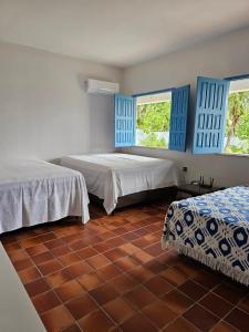 Habitación con 2 camas, ventanas azules y suelo de baldosa. en Mansão 6/4 Piscina & Mar en Olivença