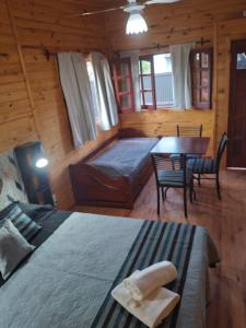 1 dormitorio con 1 cama y 1 mesa en una cabaña en D'Charrúas Cabañas Chajarí en Chajarí