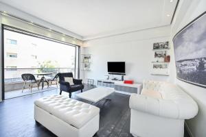 Elle comprend un salon doté d'un mobilier blanc et d'une grande fenêtre. dans l'établissement Beauty Paramount by HolyGuest, à Tel Aviv
