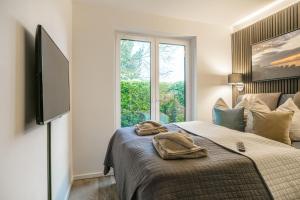 Un dormitorio con una cama con televisión y una ventana. en Baltic House Muschel, en Timmendorfer Strand