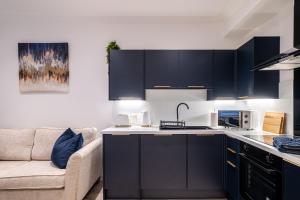 a kitchen with dark blue cabinets and a couch at Holburn Hideaway - SJA Stays - Luxury 2 Bed Apartment in Aberdeen