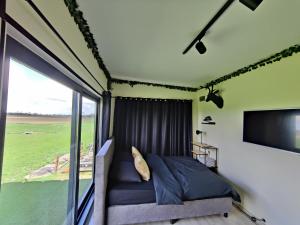 a bedroom with a bed and a large window at Tiny House Betuwe in Tricht