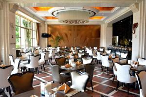 uma sala de jantar com mesas e cadeiras brancas em Days Hotel Logan City Huizhou em Huizhou