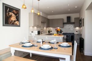 a kitchen with a dining room table with plates and glasses at Luxury Scottish Hot Tub Getaway in Gatehouse of Fleet