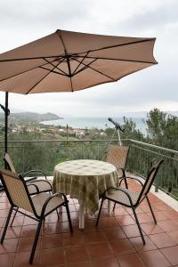 een patio met een tafel en stoelen en een parasol bij Tritsili house in Koroni