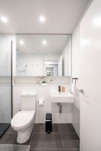 a white bathroom with a toilet and a sink at Urban Elegance 2B2B w parking, pool South Brisbane in Brisbane