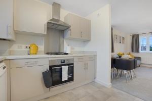 a kitchen with white cabinets and a stove top oven at Gravesend 2 Bed Apartment-2 minutes walk from shops, Restaurants and Motorway. Sleep upto 5 in Northfleet