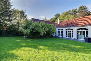 una casa con un gran patio con un gran árbol en Le cosy Cottage du chêne en Lasne