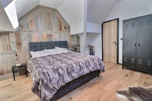 ein Schlafzimmer mit einem Bett und einer Holzwand in der Unterkunft Le cosy Cottage du chêne in Lasne