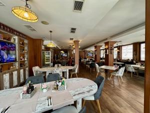 ルセにあるホテル コスモスのテーブルと椅子が備わるウッドフロアのレストランを併設しています。