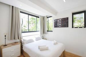 a bedroom with a white bed and two windows at Design 2BR in Dizengoff st by HolyGuest in Tel Aviv