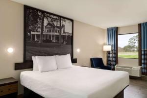 a hotel room with a bed and a picture of a house at Super 8 by Wyndham Ocean Springs Biloxi in Ocean Springs