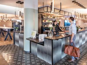 a man and woman standing at a bar in a restaurant at Novotel Marne-la-Vallée Noisy-le-Grand in Noisy-le-Grand