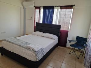 um quarto com uma cama, uma cadeira e janelas em Sigma Theta Homes - KNUST Area em Kumasi