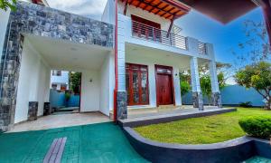 a house with a red door and a green yard at Newolivevilla in Katunayake